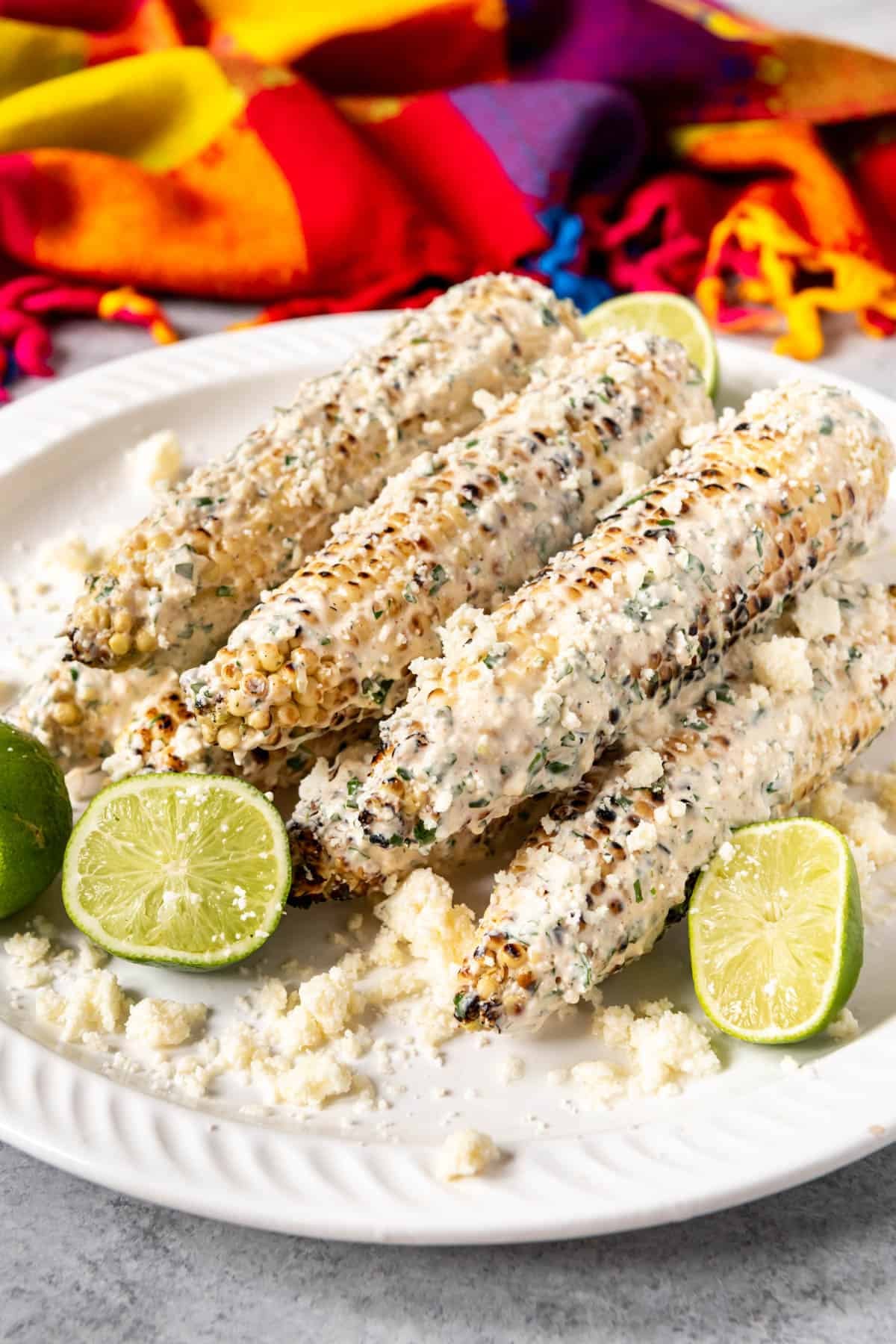 Limes around street corn on a plate.