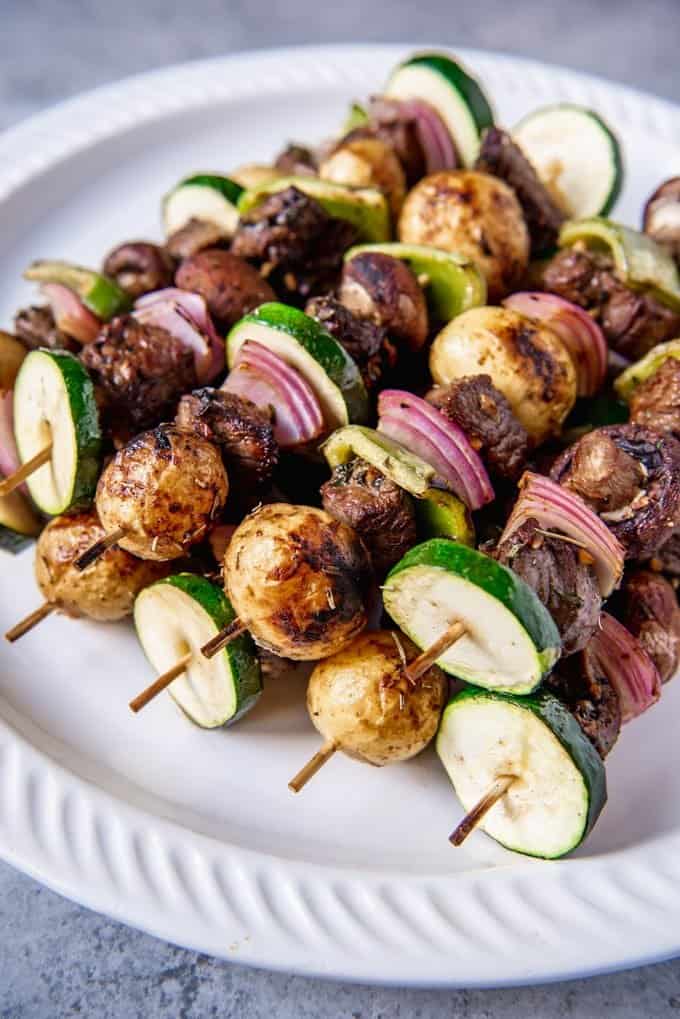 a pile of beef and vegetable skewers on a white plate