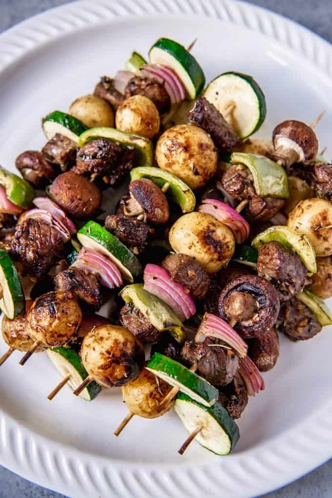 An image of a skewered sirloin steak cubes grilled with onions, peppers, mushrooms, and potatoes for beef shish kabobs.