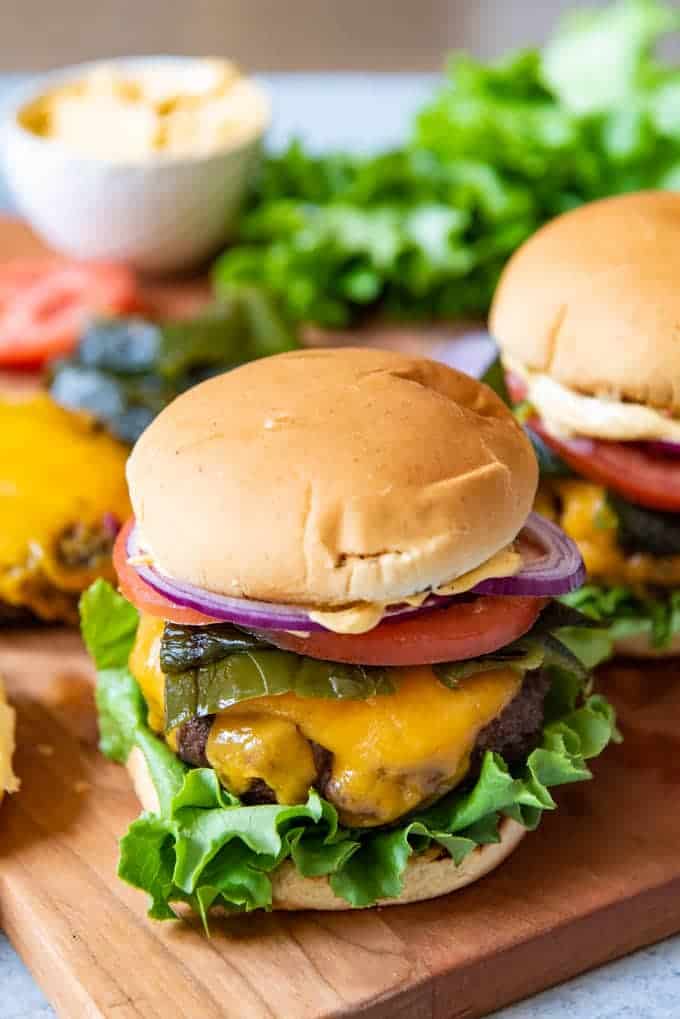 A juicy cheeseburger topped with grilled poblano peppers, lettuce, tomatoes, red onions, and homemade chipotle aioli makes the most amazing southwest burgers.