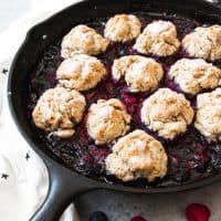 a cast iron skillet with berr cobbler and biscuits