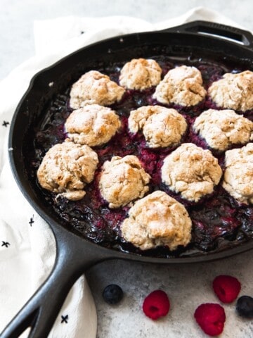 a cast iron skillet with berr cobbler and biscuits
