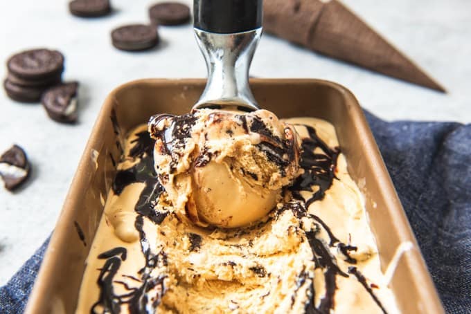 An image of a scoop of caramel ice cream with a fudge swirl and crushed oreo pieces.