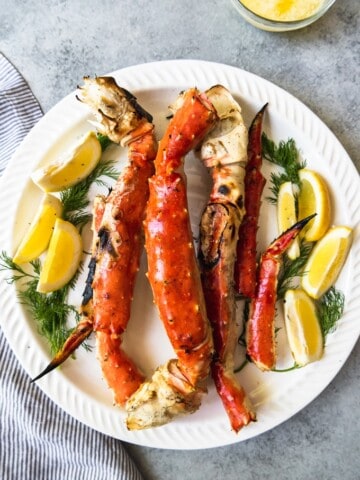an aerial view of a plate filled with cooked crab legs and garnished with lemon slices and fresh herbs
