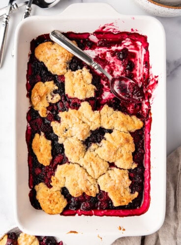 An overhead image of a mixed berry cobbler in a white baking dish.