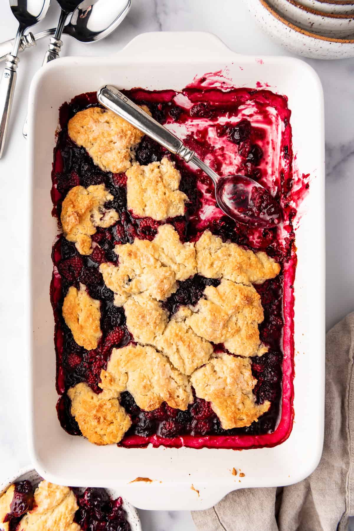 An overhead image of a mixed berry cobbler in a white baking dish.