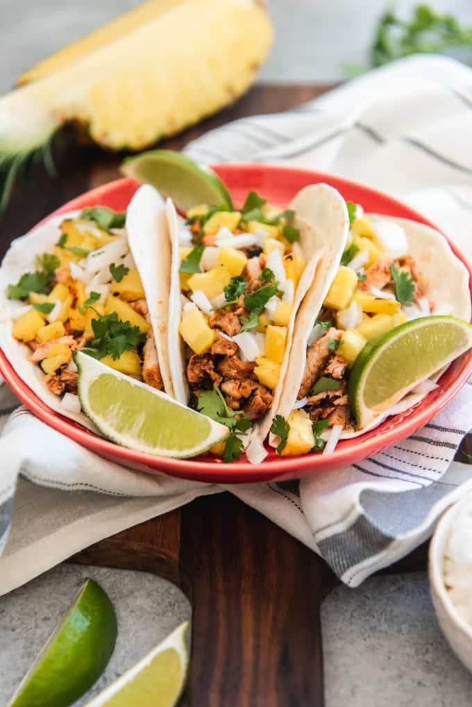 a plate of three tacos garnished with lime wedges