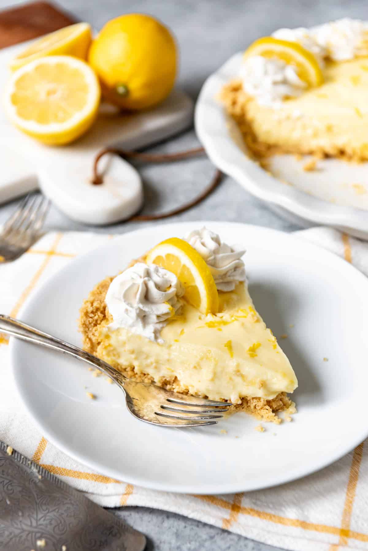 An image of a no-bake pie with a golden Oreo crust, filled with a creamy sour cream lemon pie filling and topped with sweetened whipped cream.