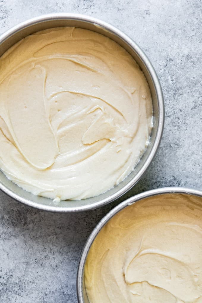 An image of yellow cake batter in two round 8-inch cake pans.
