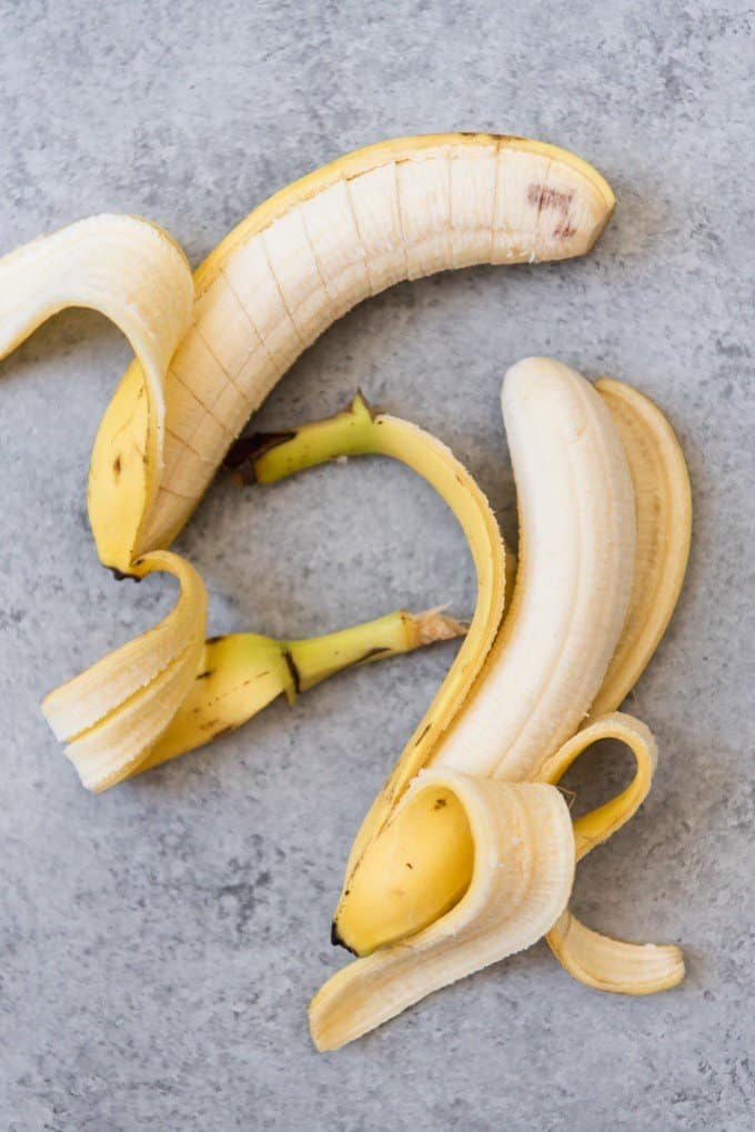 An image of two peeled bananas, with one sliced into ½" discs.