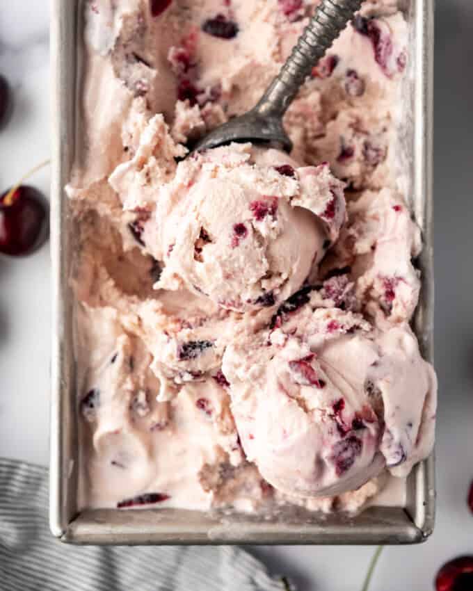 An overhead image of a batch if black cherry ice cream with a scoop.