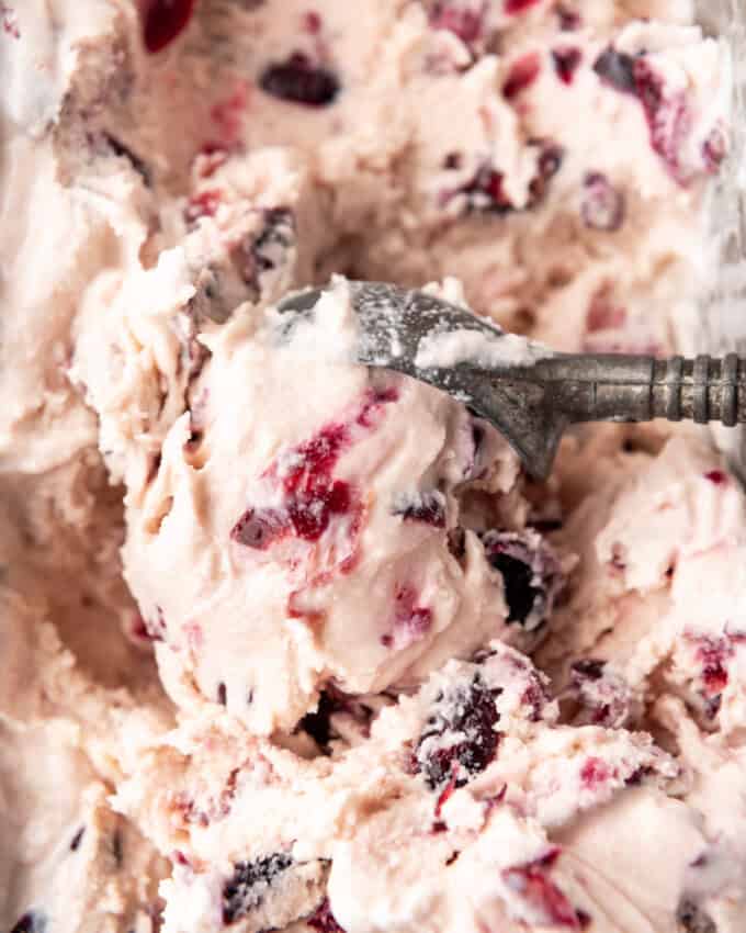 An overhead image of an ice cream scooper scooping black cherry ice cream.