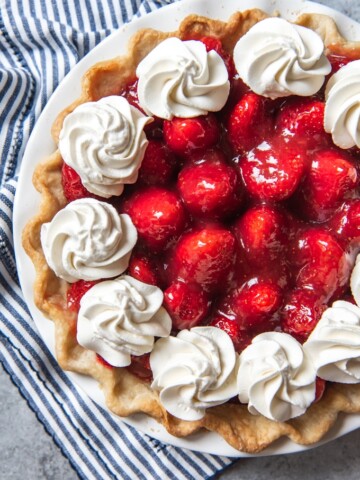 glossy fresh strawberry pie with whipped cream around the edges