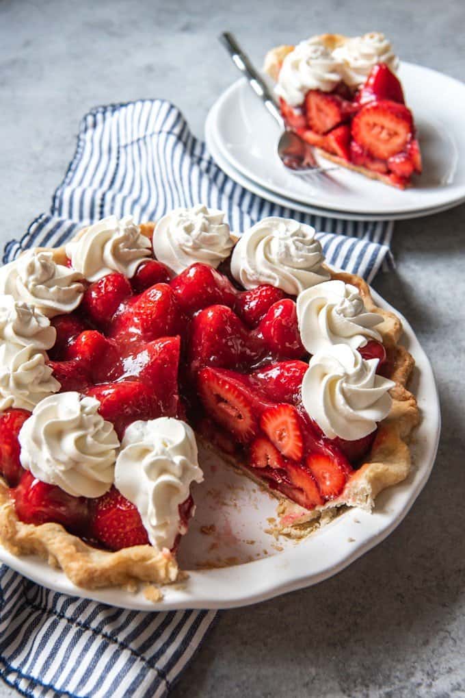 a sliced strawberry pie with whipped cream