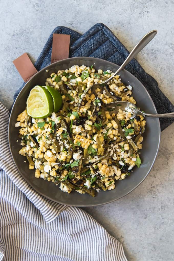 An image of a chopped grilled cactus and corn salad in a grey serving dish.