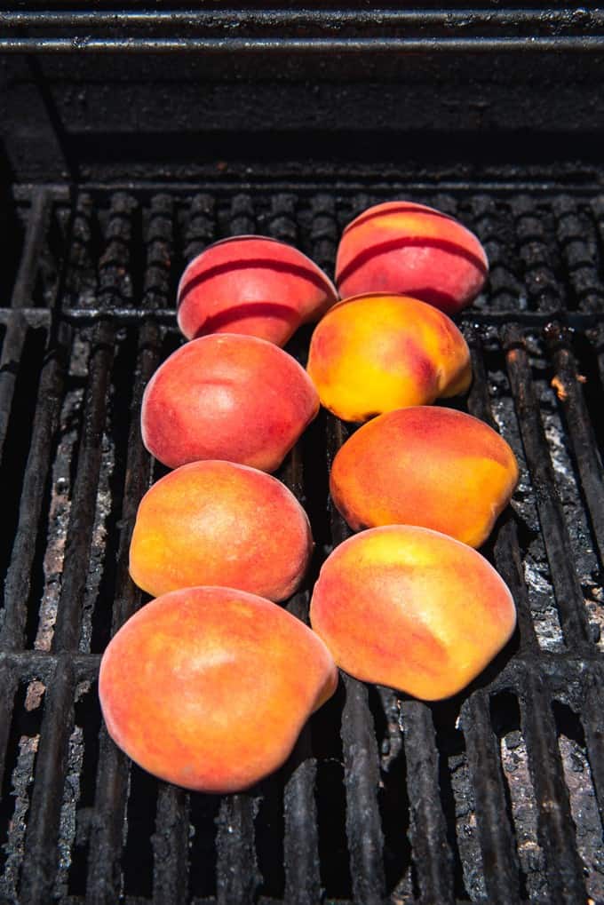 An image of 8 peach halves on a hot grill being grilled to add to a salad or topped with ice cream.