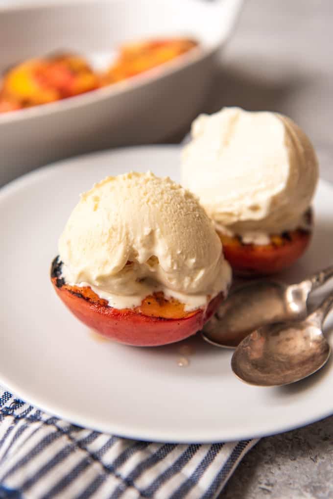 a plate with two spoons and two peaches with ice cream