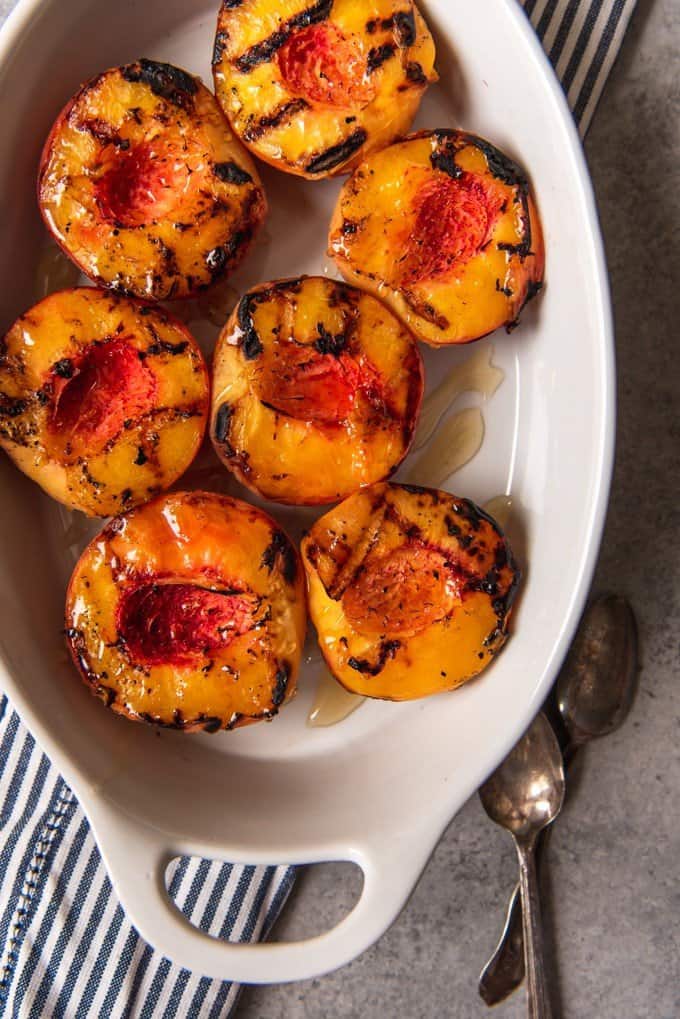 An image of a dish full of grilled peaches drizzled with honey.