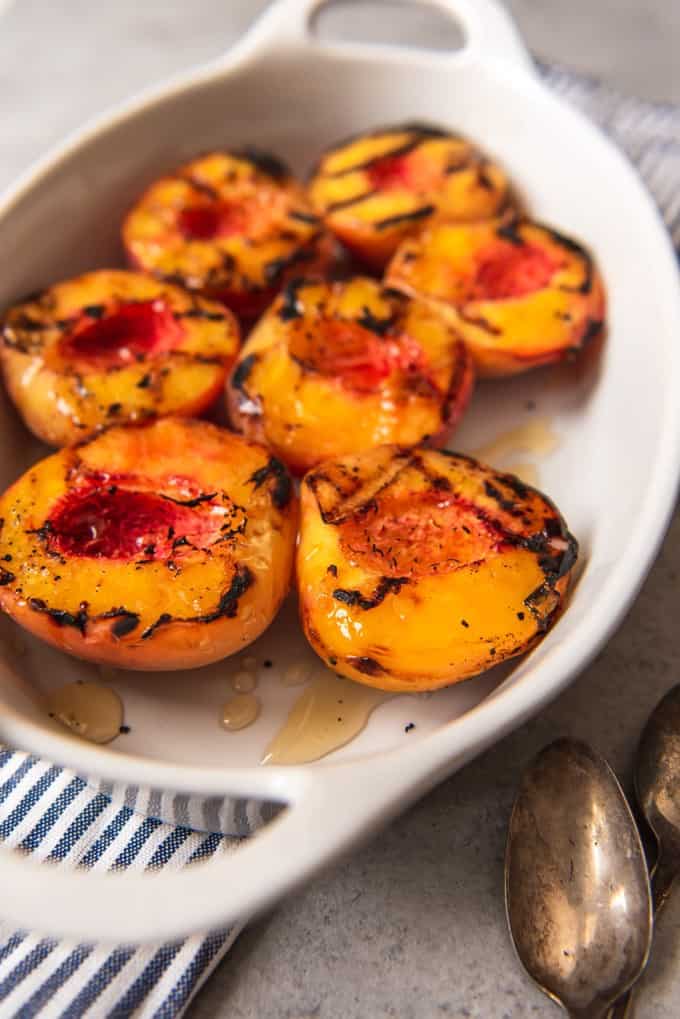 grilled peach halves in a white baking dish