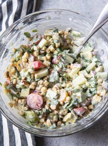 a glass bowl filled with creamy summer corn salad