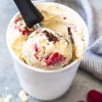 White Chocolate Raspberry Truffle Ice Cream in a white container with an ice cream scoop inside