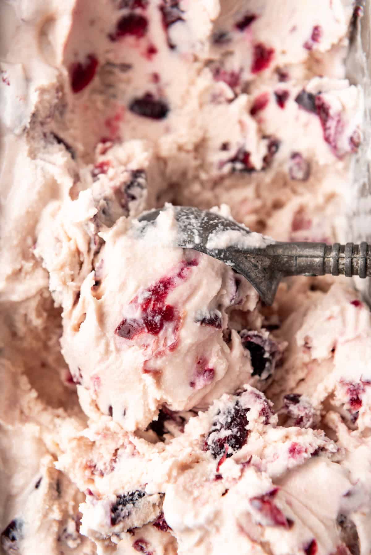 An overhead image of an ice cream scooper scooping black cherry ice cream.