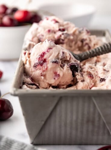 A side view of scoops of black cherry ice cream in the container.