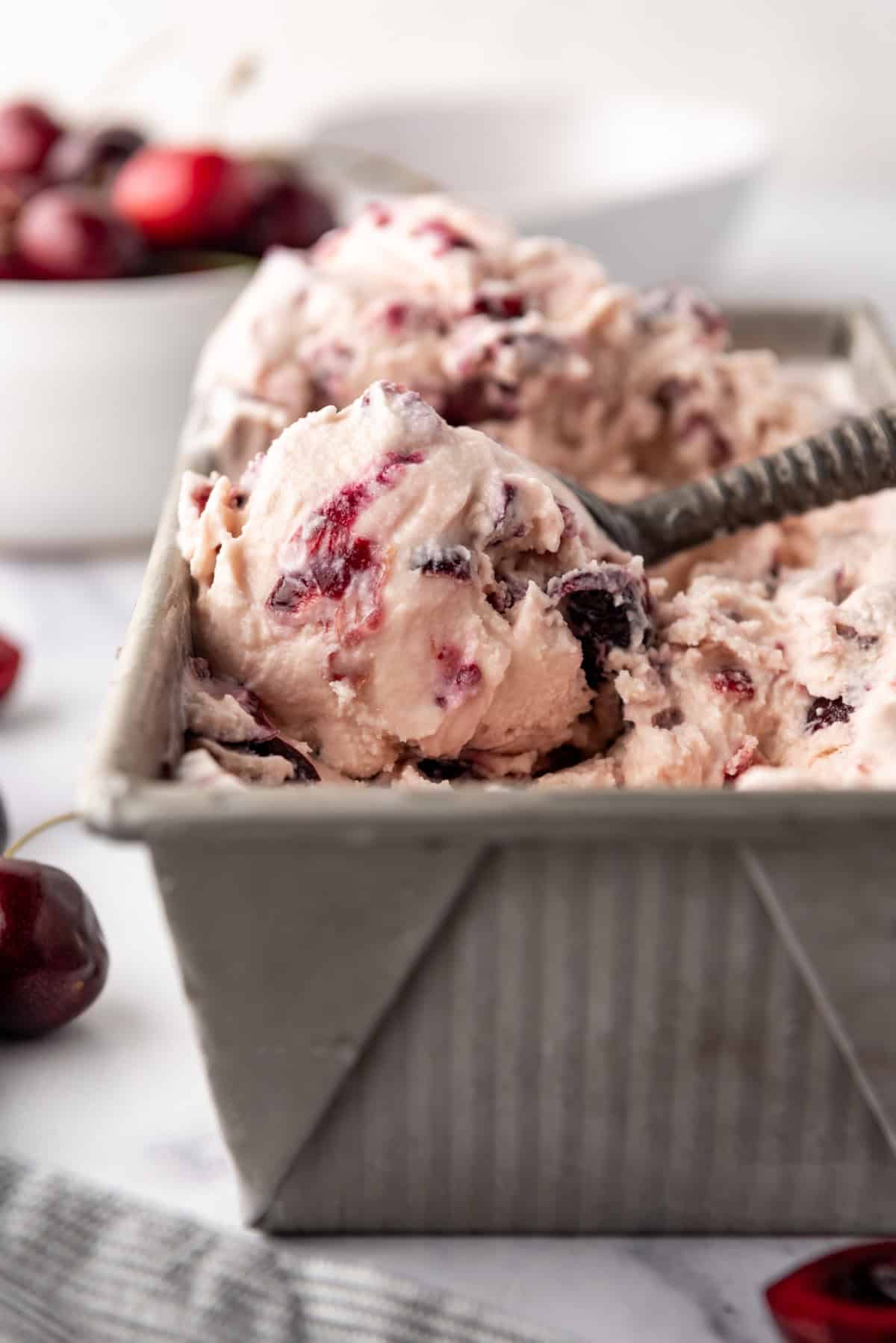 A side view of scoops of black cherry ice cream in the container.