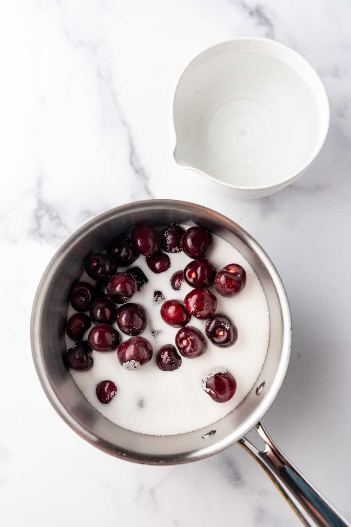 Combining cherries, sugar, and water in a saucepan.