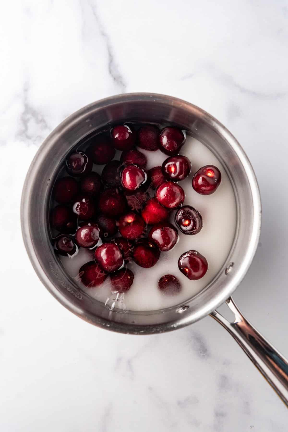 Combining cherries, sugar, and water in a saucepan.