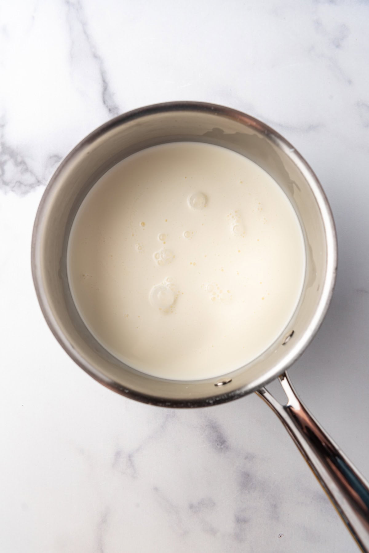 Heating milk, cream, and sugar in a saucepan.