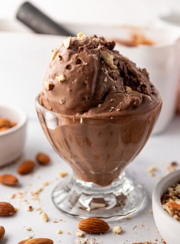 Scoops of burnt almond fudge ice cream in a glass sundae dish.