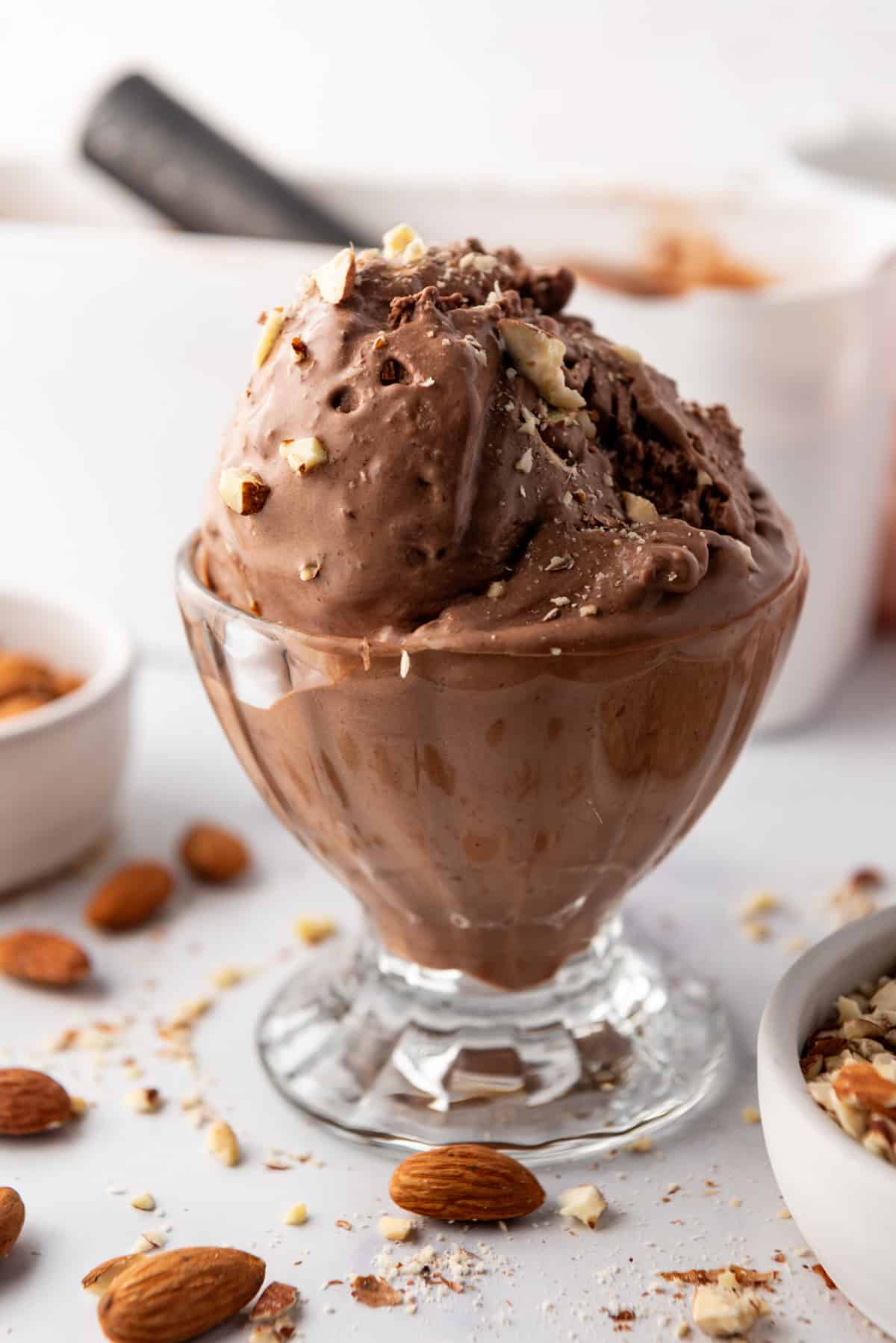 Scoops of burnt almond fudge ice cream in a glass sundae dish.