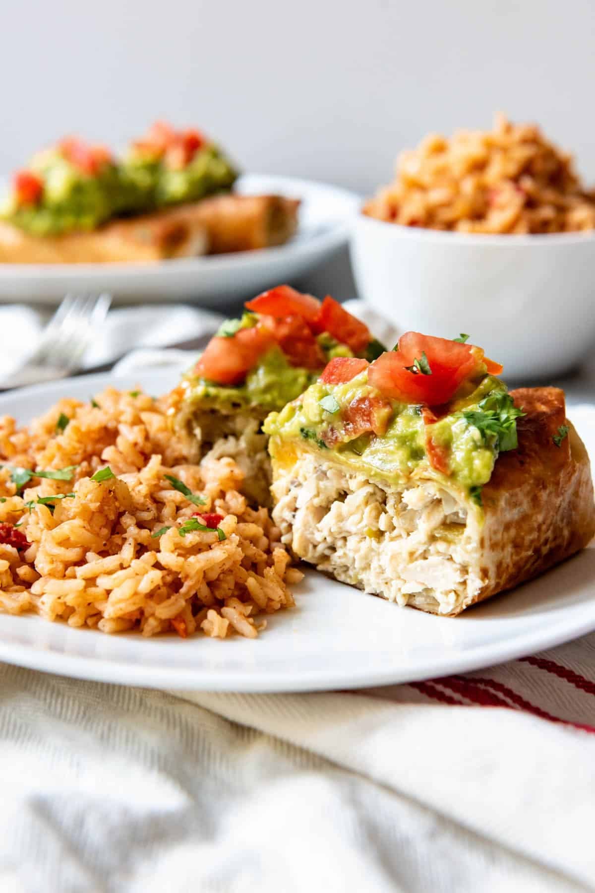 An image of a chicken chimichanga sliced open and served with Spanish rice.