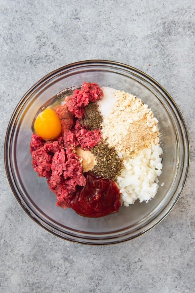 An image of the ingredients for meatloaf in a bowl, ready to be mixed by hand and then shaped into meatloaf patties.