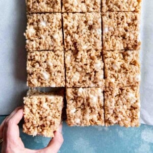 An image of a hand reaching for a salted brown butter rice krispie treat square.