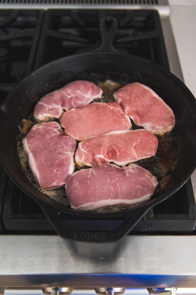 cooking pork chops in a cast iron skillet on the stove