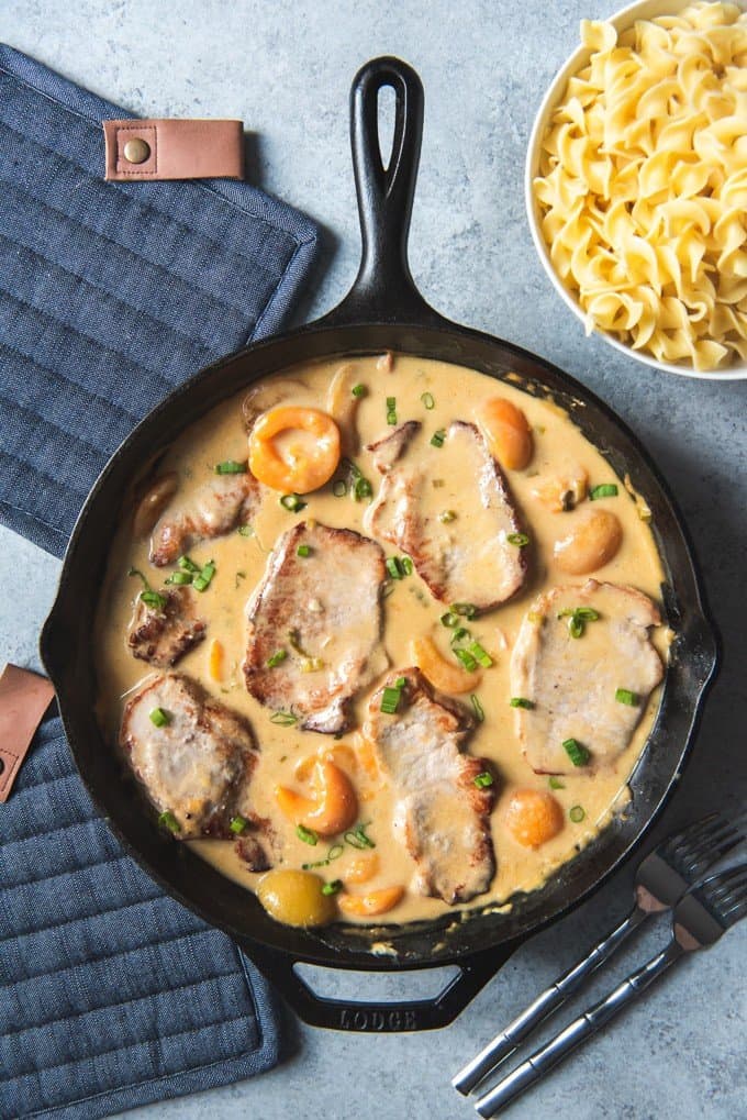 an aerial view of a cast iron skillet full of creamy apricot porkchops