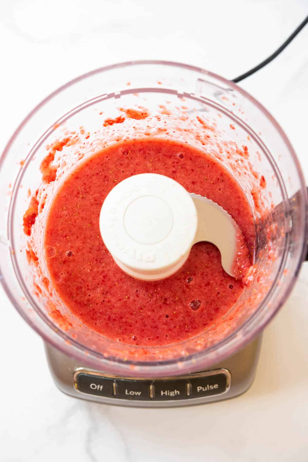 Pureeing strawberries in a food processor.