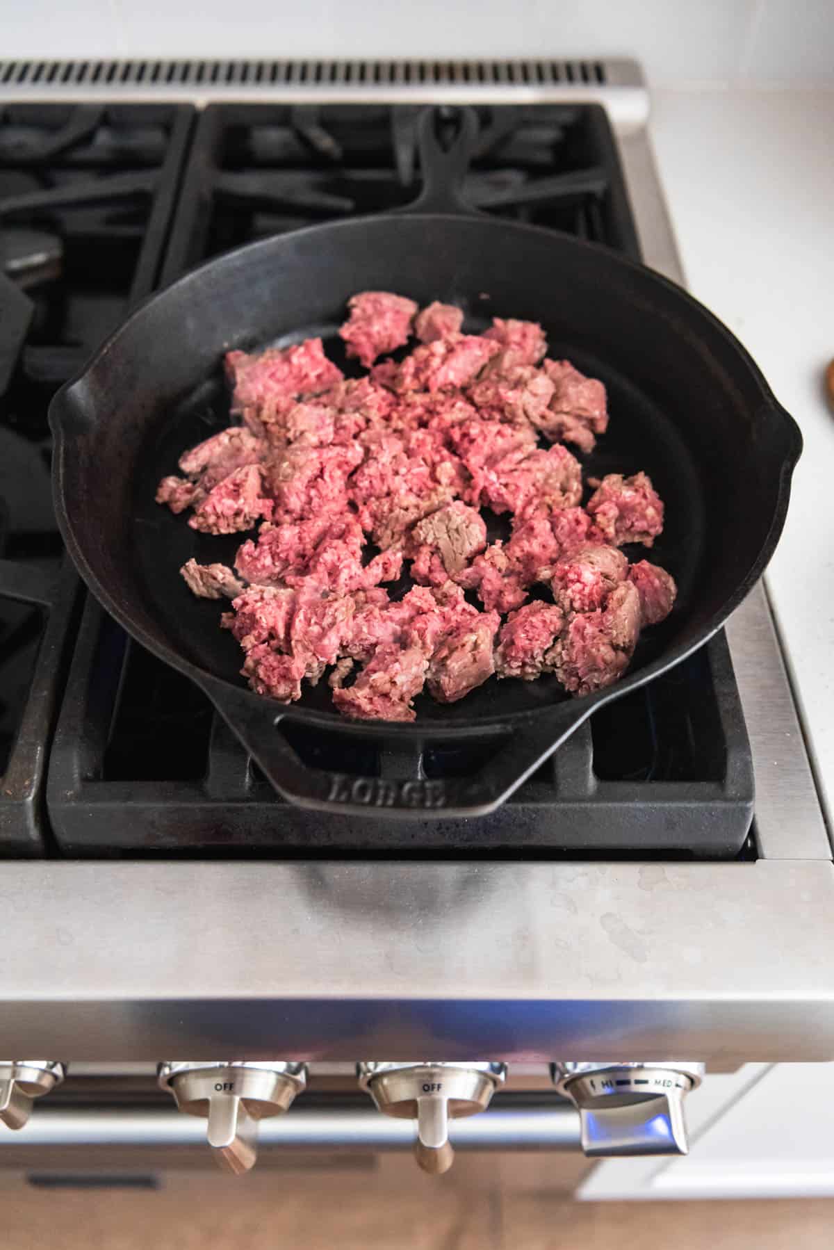 An image showing how to brown ground beef in a cast iron pan.