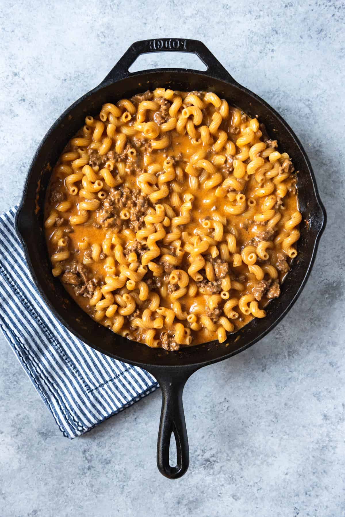 An image of cheesy pasta noodles and ground beef with spices in a pan.
