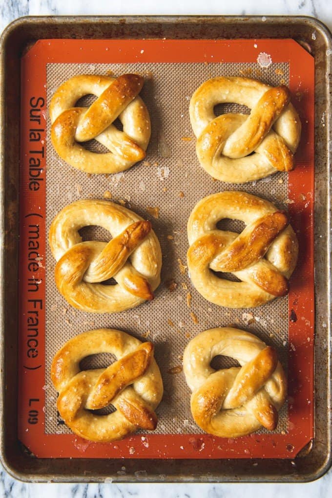 An image of six homemade soft pretzels brushed with melted butter and sprinkled with salt.