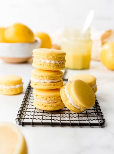 An image of lemon macarons stacked on top of one another on a baking cooling rack.