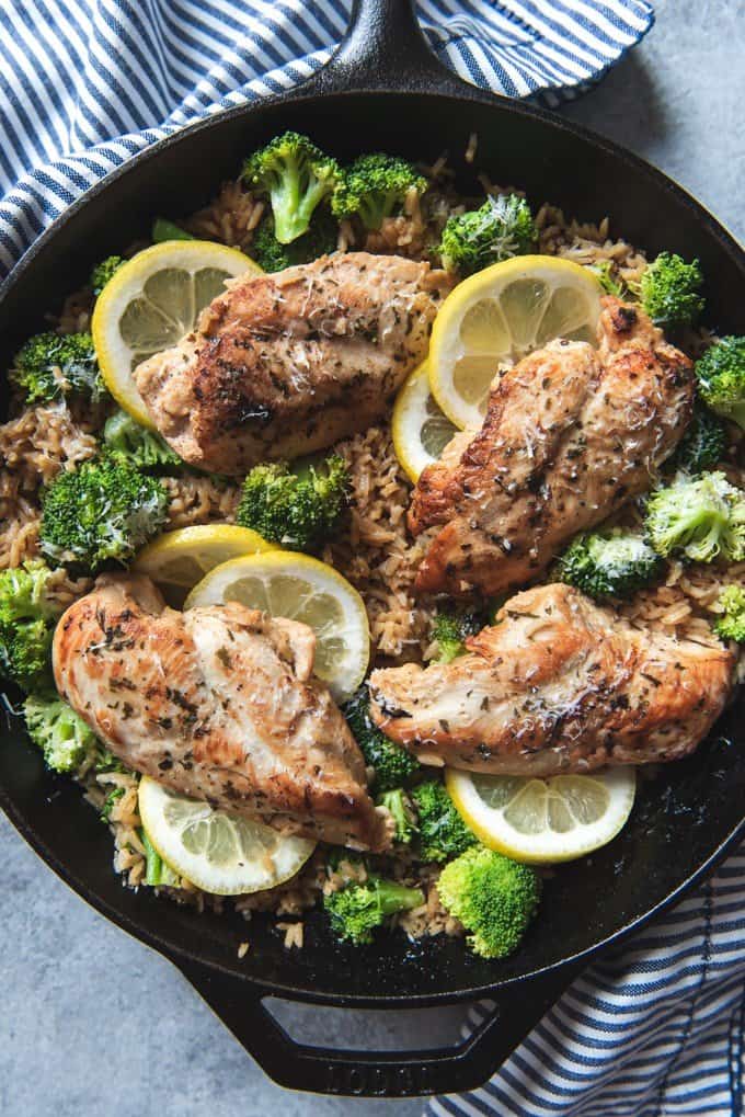 An image of a healthy chicken and rice recipe with lemons and broccoli in one skillet.