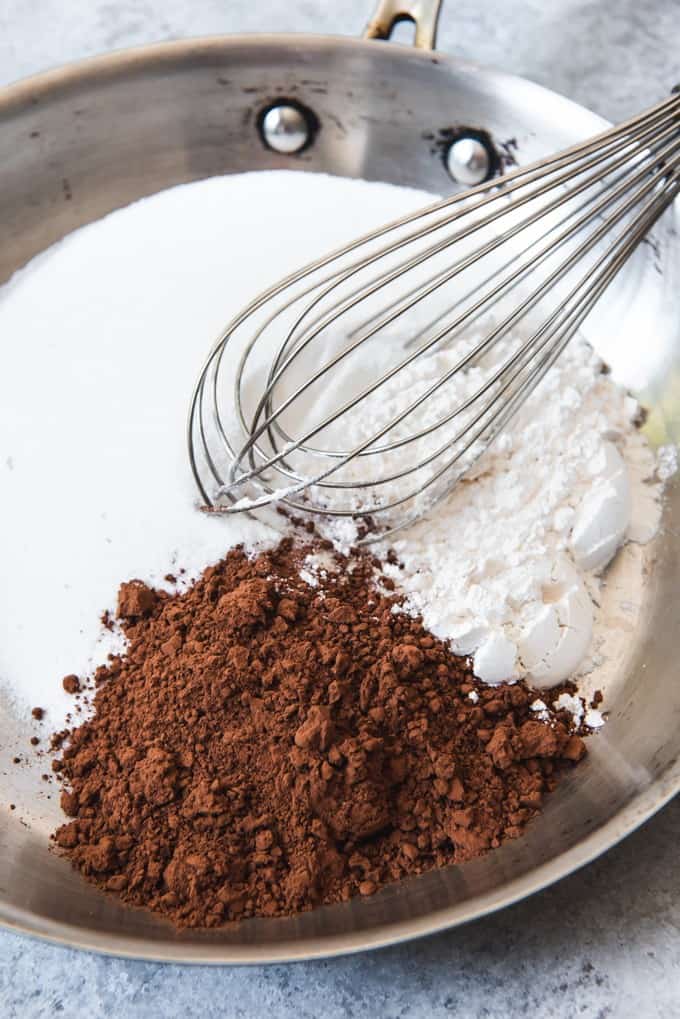 An image of sugar, cocoa powder, and flour in a pan with a whisk for making southern chocolate gravy from Arkansas.