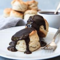chocolate gravy smothered southern biscuits on a white plate with more biscuits in the background