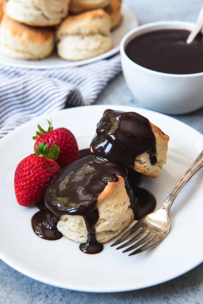An image of the best homemade buttermilk biscuits covered in chocolate gravy and served with strawberries.