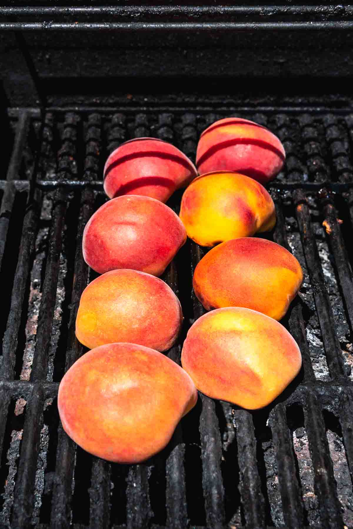 An image of 8 peach halves on a hot grill being grilled to add to a salad or topped with ice cream.