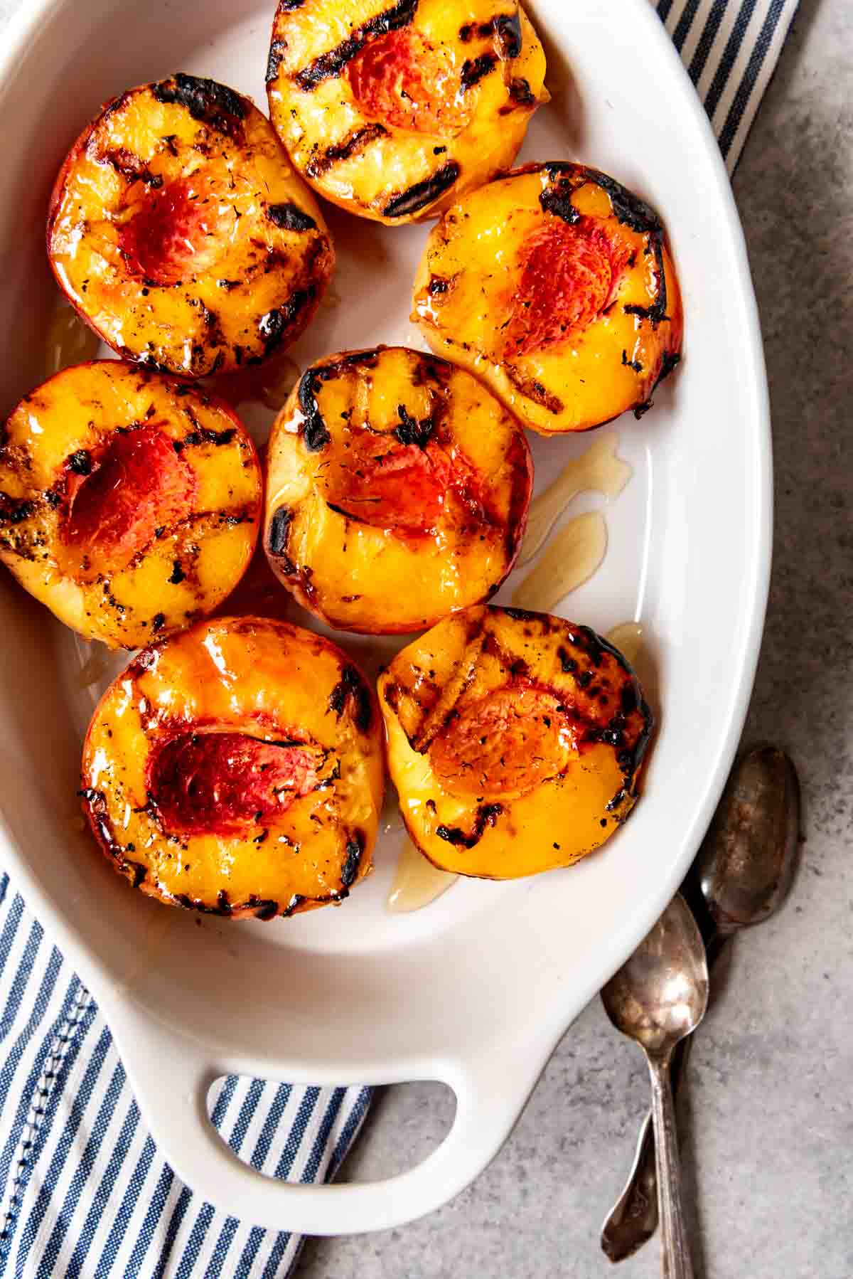 An image of a dish full of grilled peaches drizzled with honey.