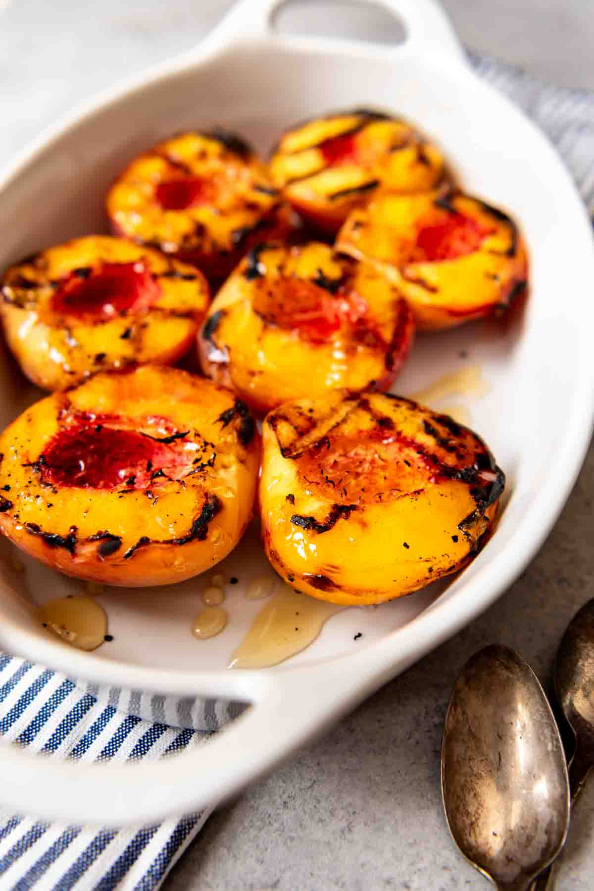 grilled peach halves in a white baking dish